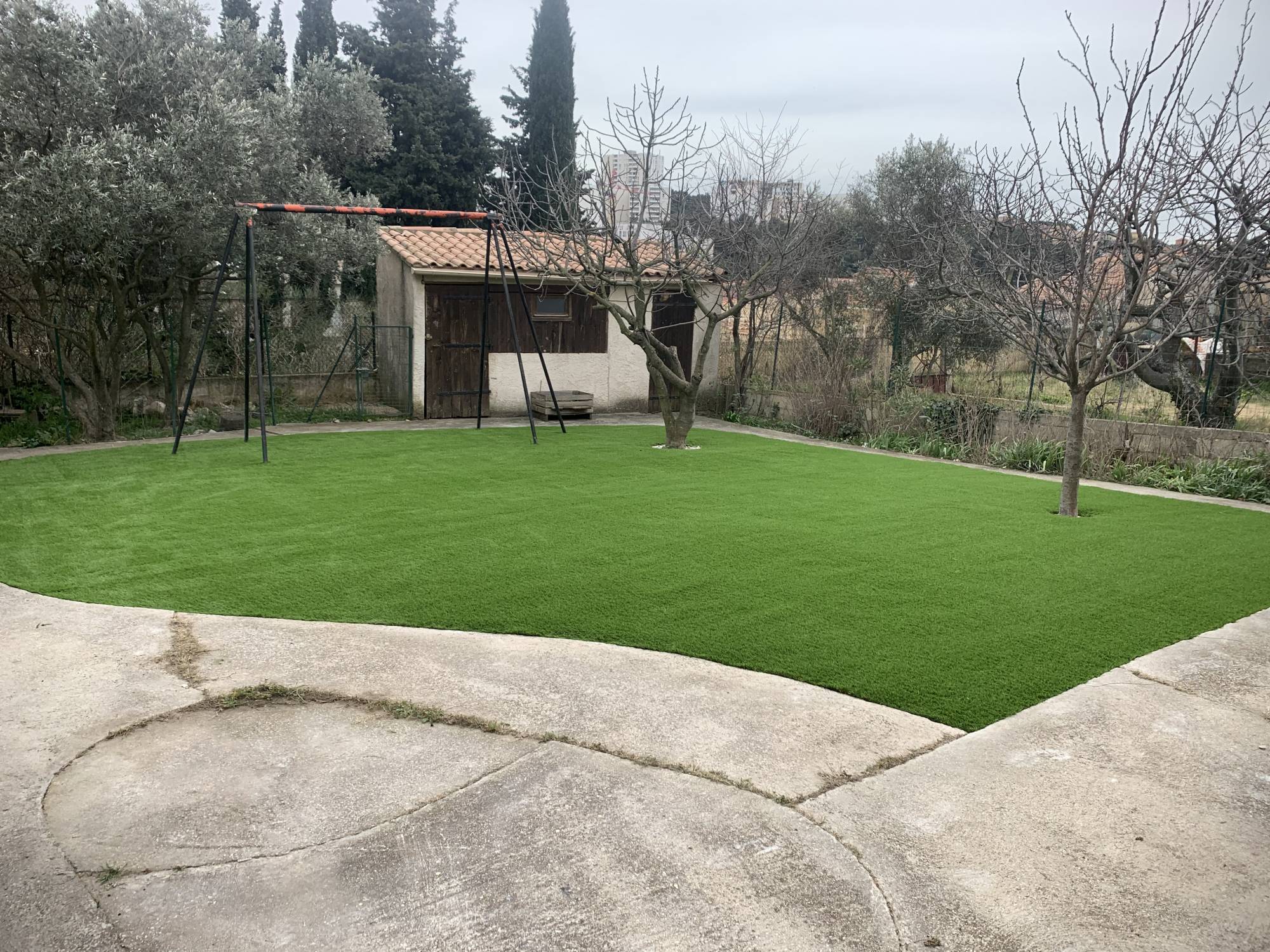 pose de gazon synthétique à mémoire de forme dans un jardin à Marseille