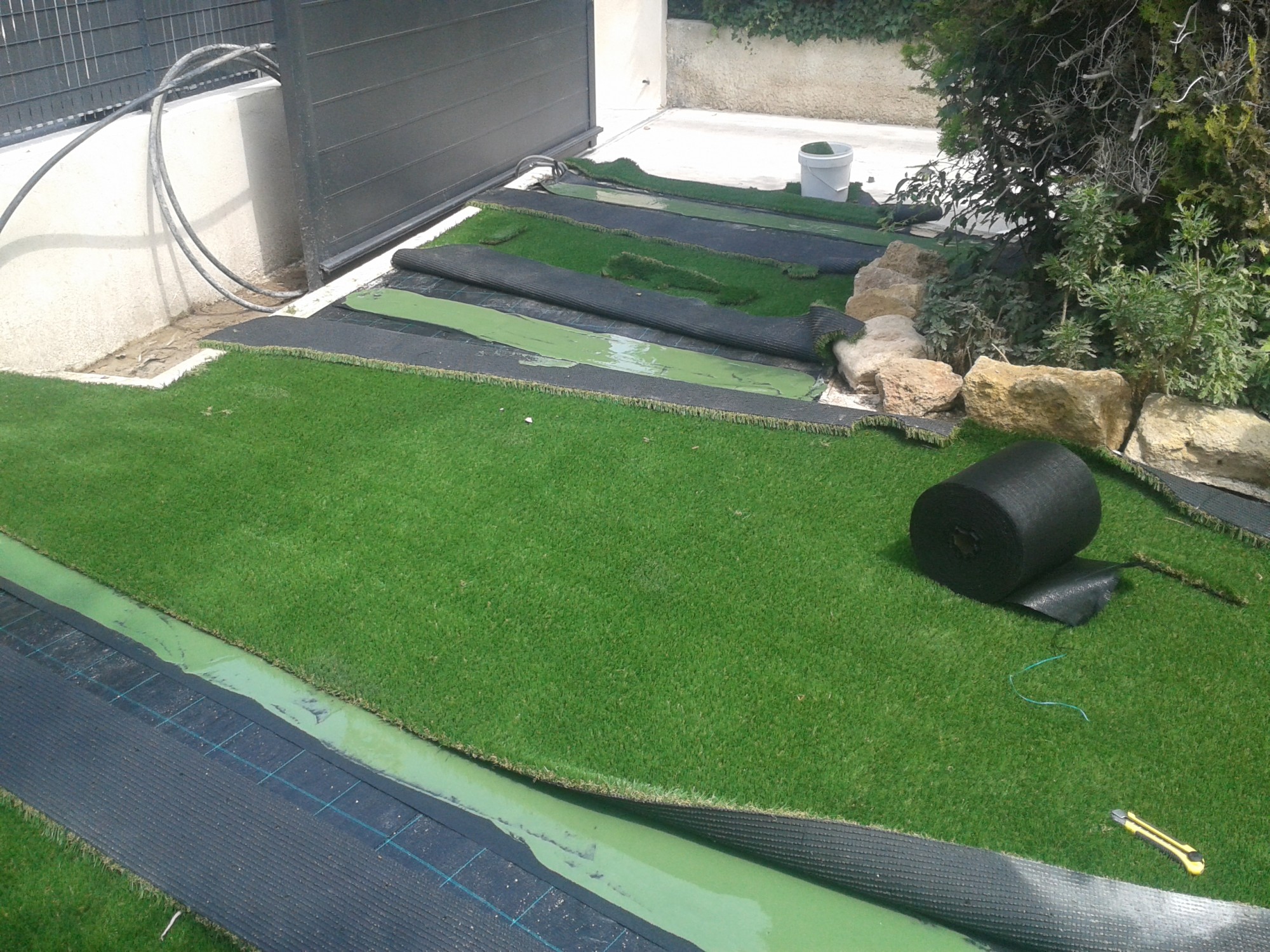 Colle des lés de ce gazon synthétique à mémoire de forme